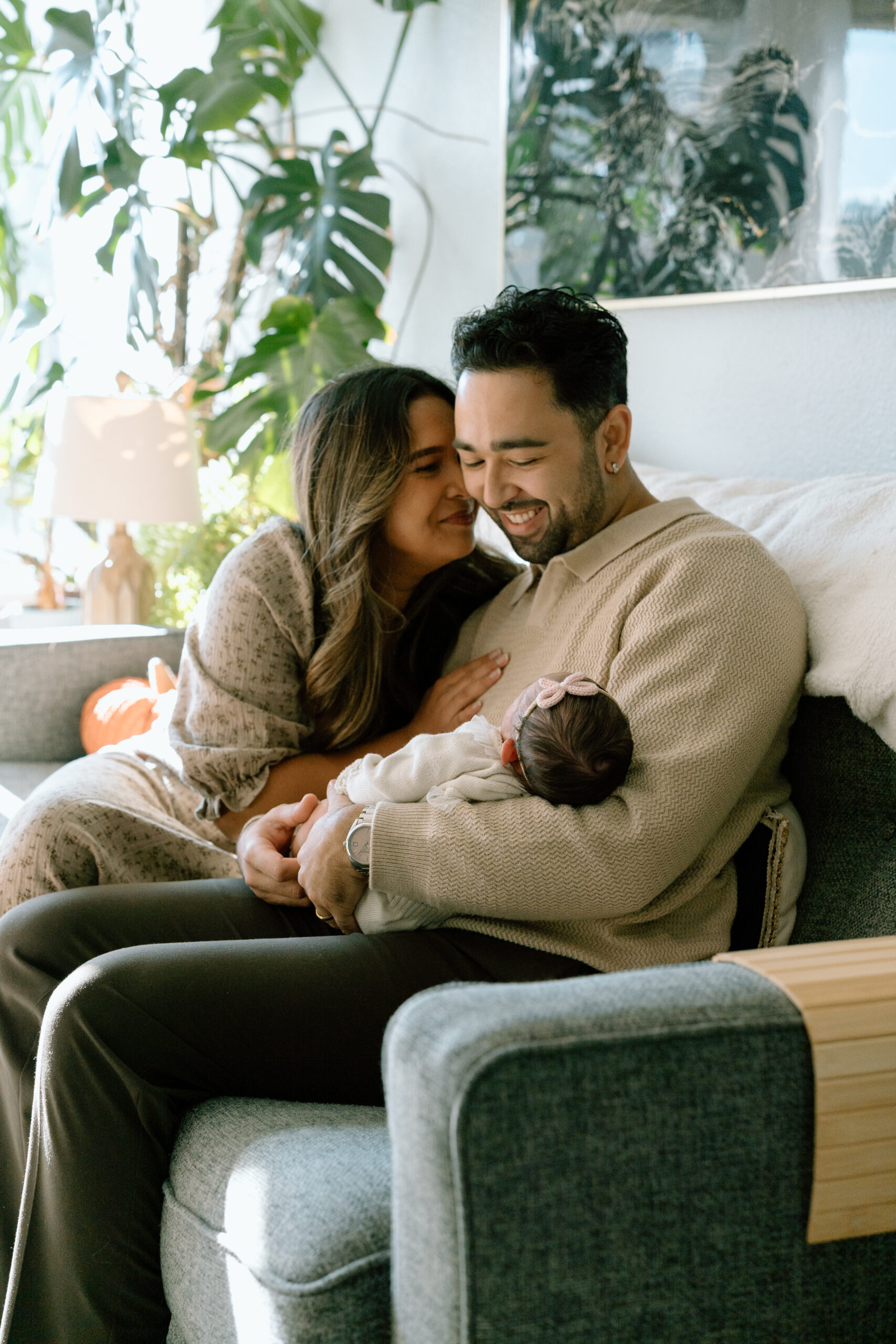 A mom and dad snuggle up with a newborn in arms.